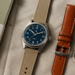 belle montre homme posée sur tissu beige avec accessoires