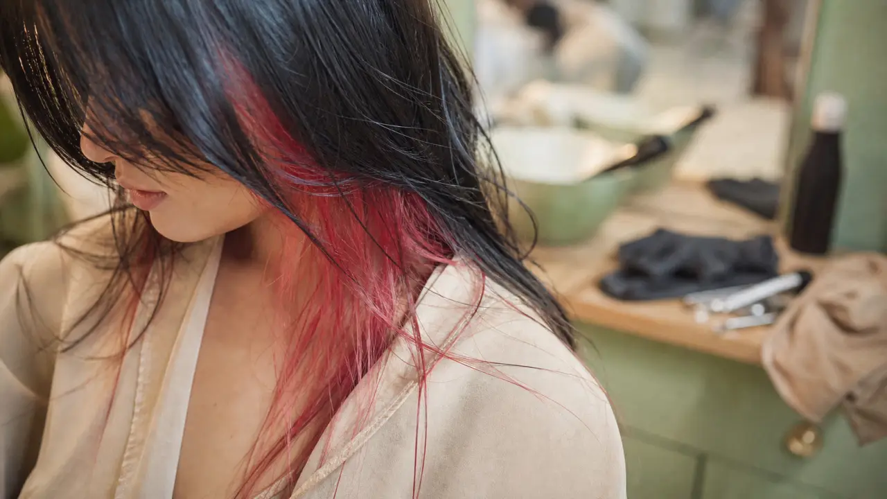 Cheveux noir avec mèche rouge cerise en salon de coiffure