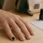 Vernis à ongle homme signification : main masculine avec vernis noir mat